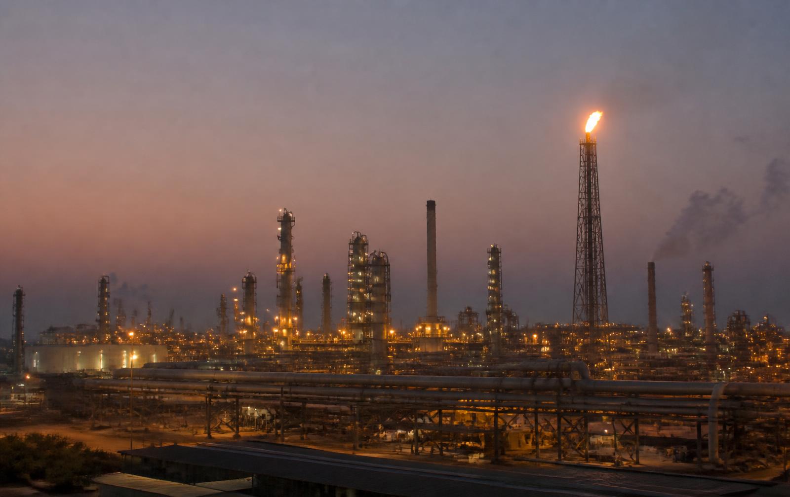 Petrochemical complex near Port Qasim, Karachi at dusk with flare stack and pipe racks