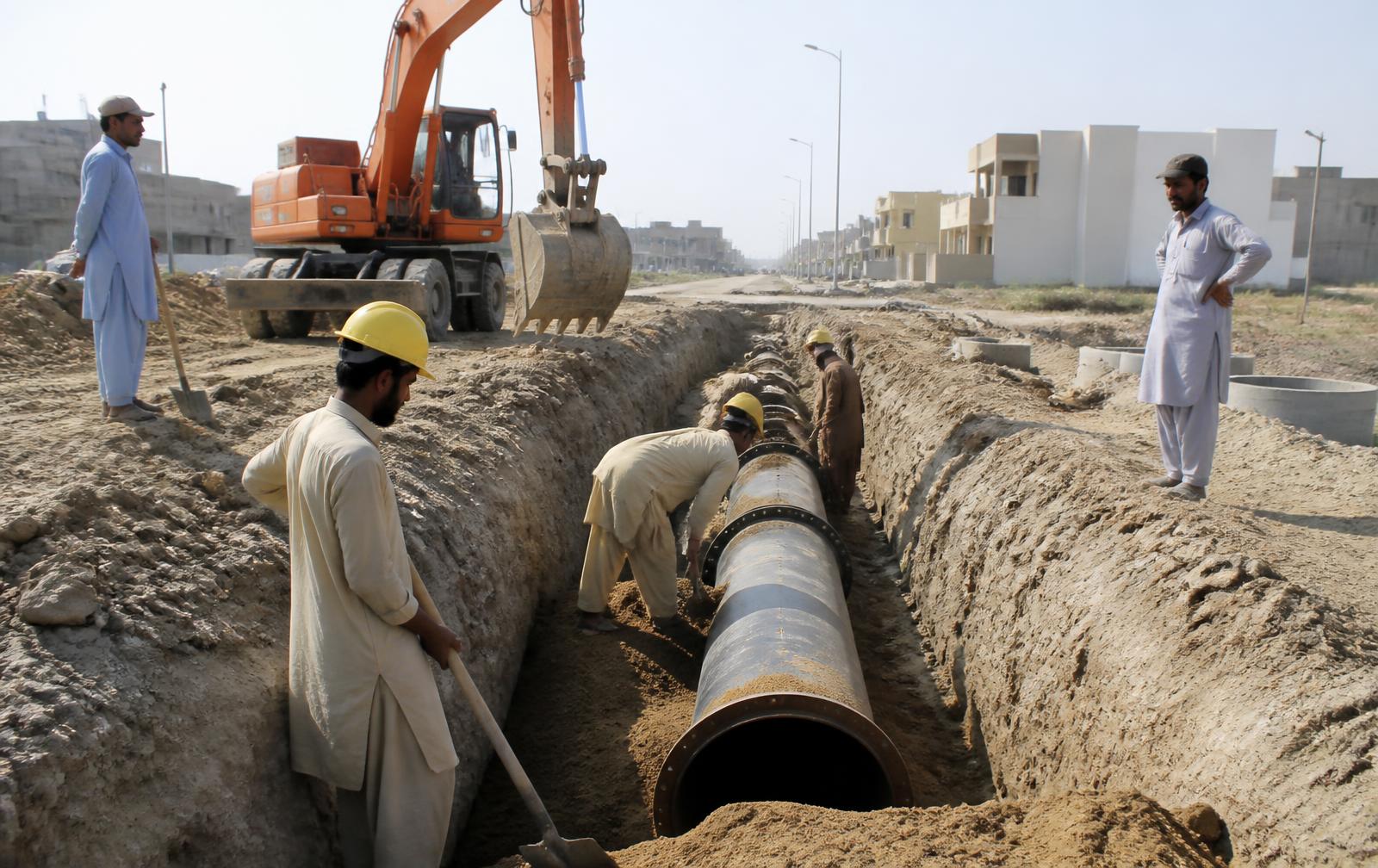 Ductile iron water main being laid in a trench in a Pakistani housing scheme